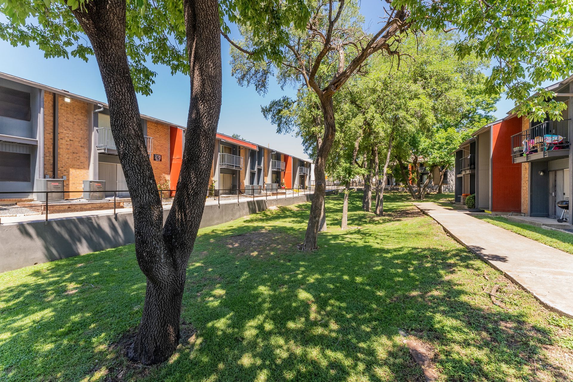 A row of apartment buildings with trees in front of them.