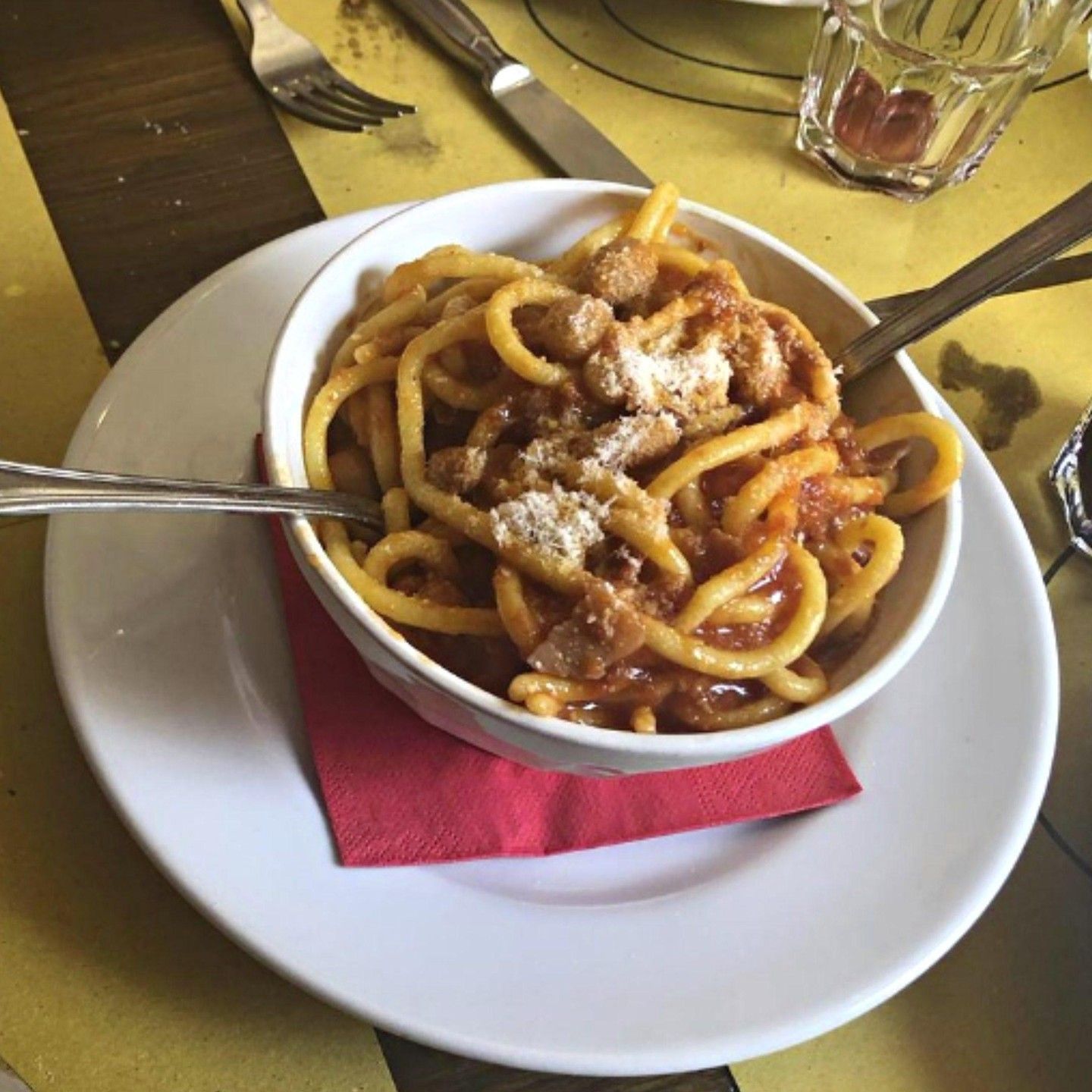 Una ciotola di spaghetti su un piatto bianco con una forchetta
