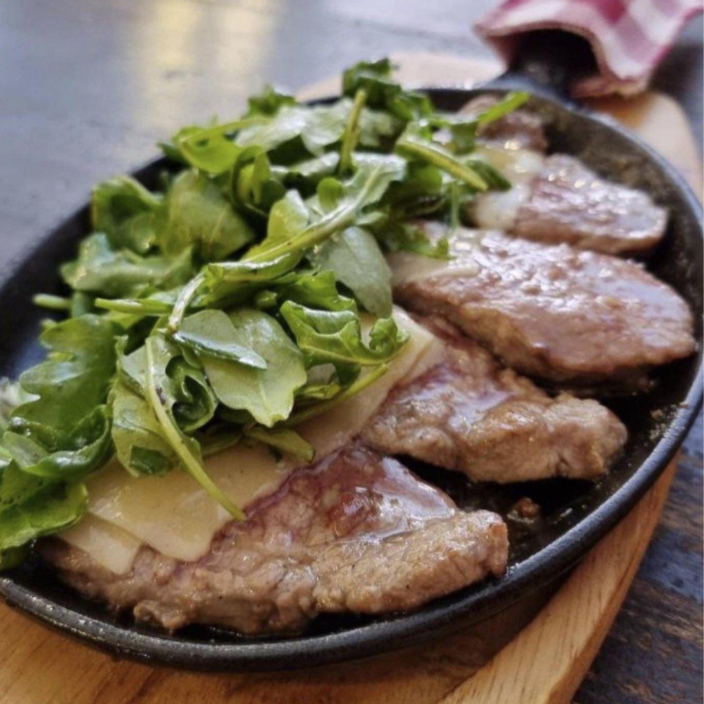 Una padella piena di carne e verdure su un tavolo di legno