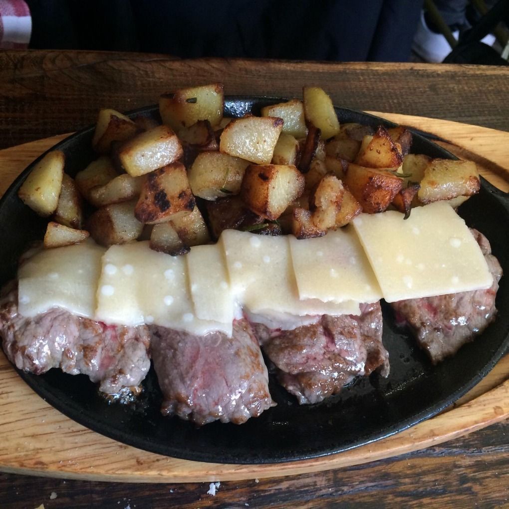 Un piatto di cibo con carne e patate su un tavolo di legno