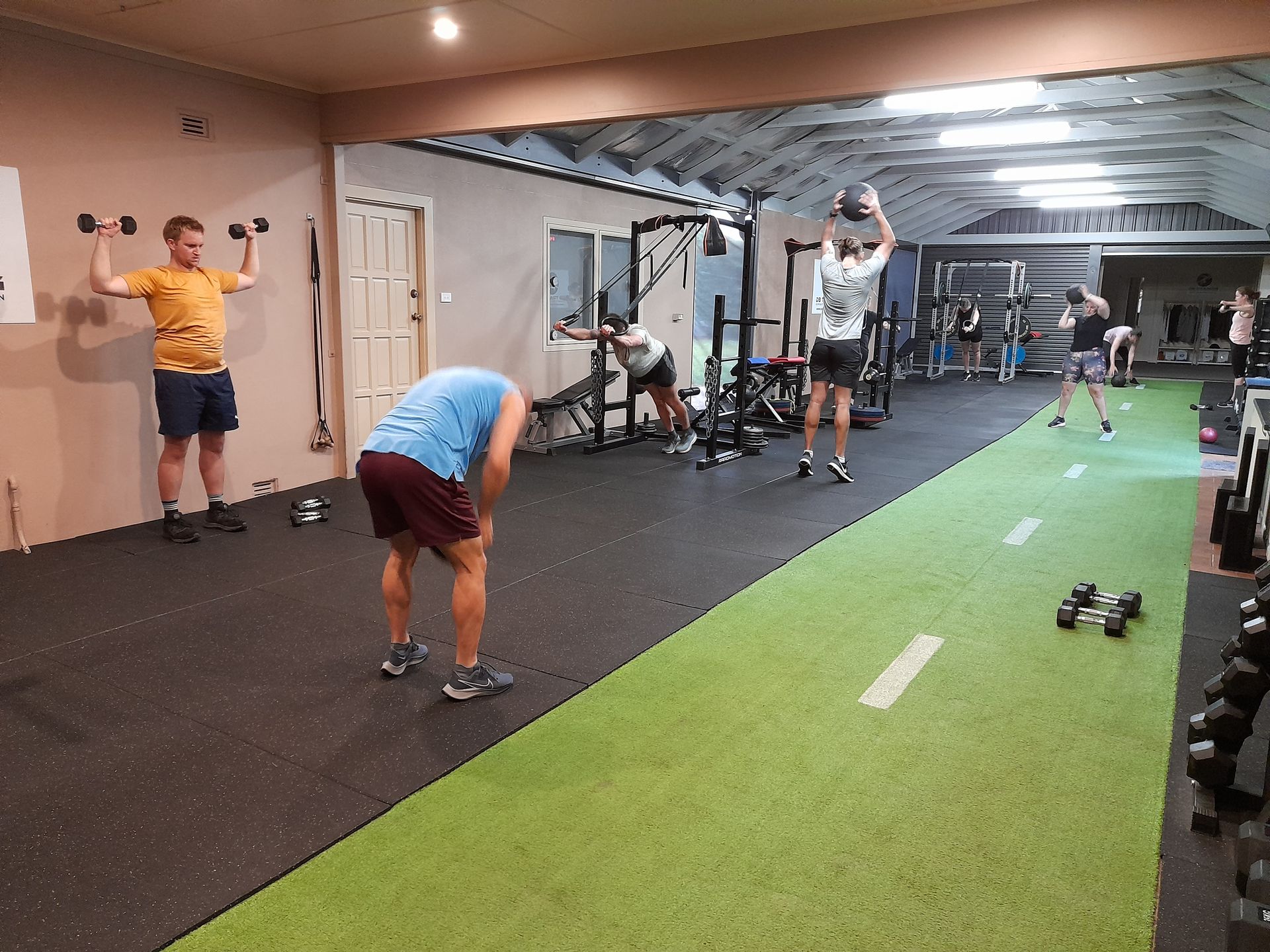 A woman is squatting on a platform in a gym.