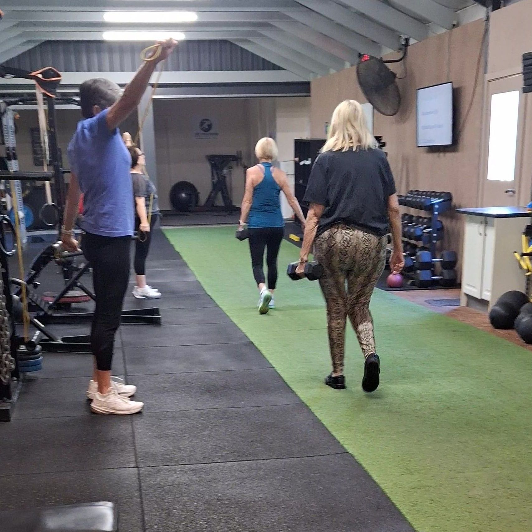 A woman is squatting on a platform in a gym.