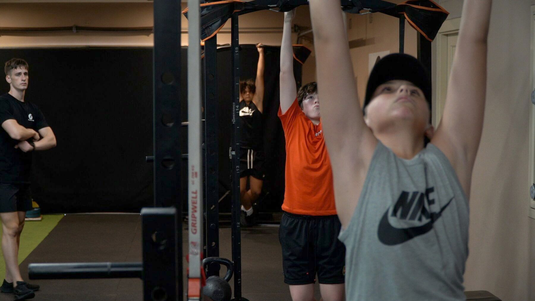 A group of young men are doing pull ups in a gym.
