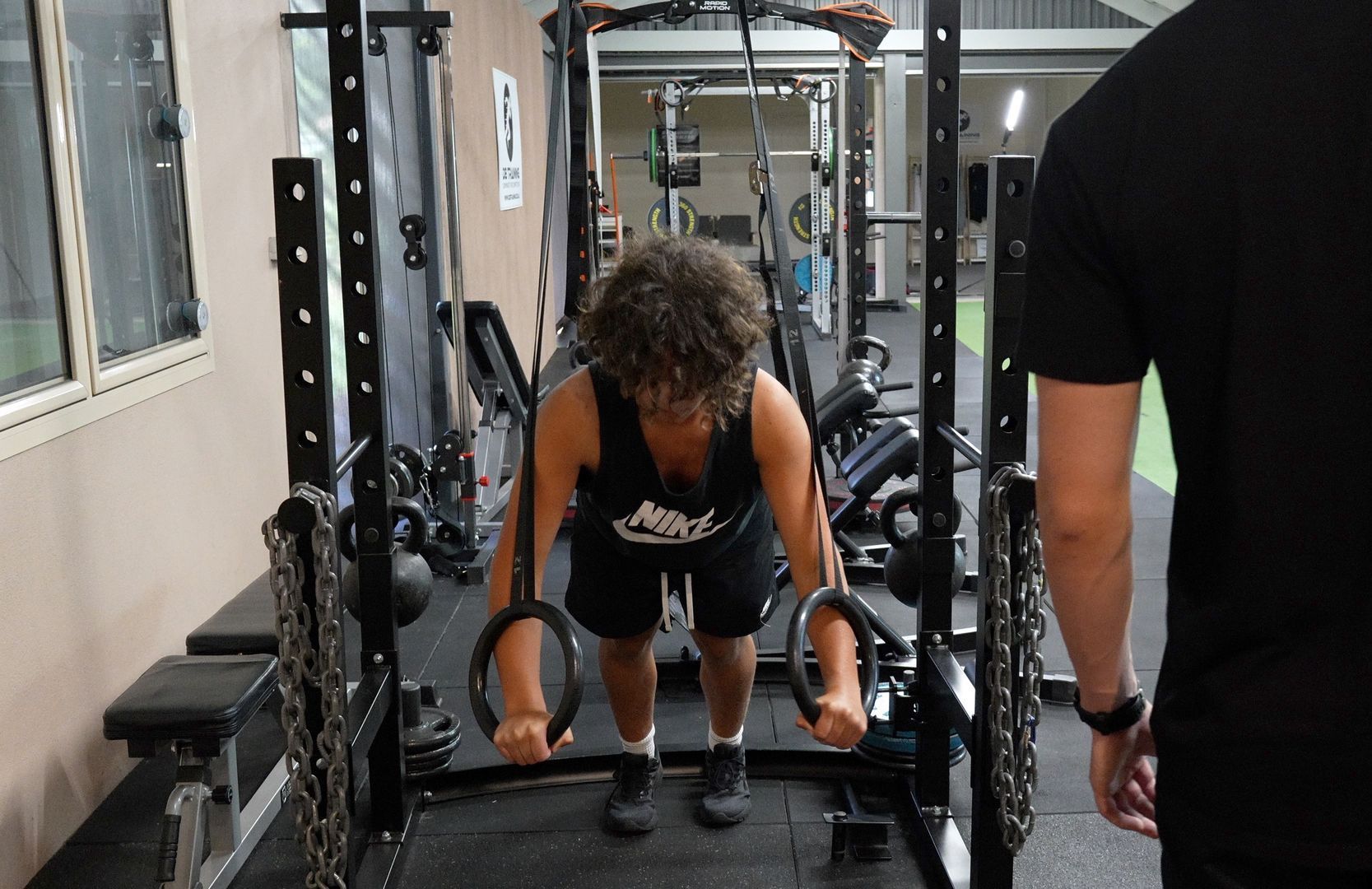 A woman is squatting on a platform in a gym.
