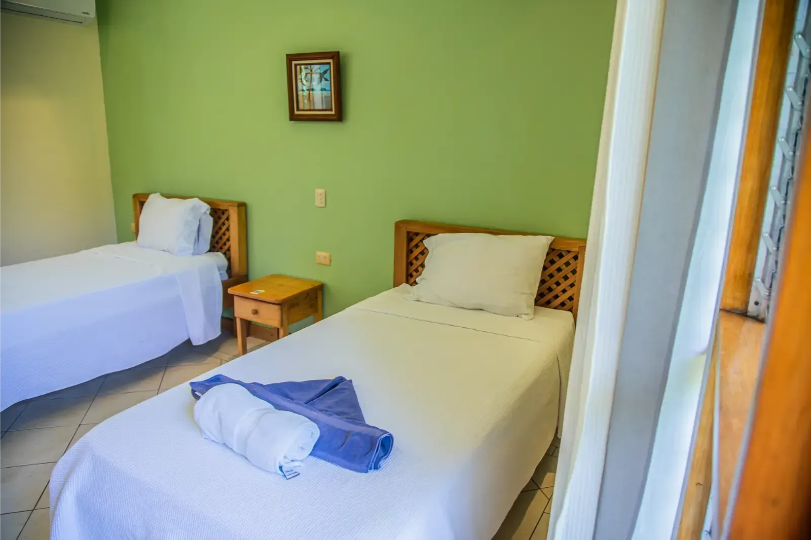 Two twin beds in a room with green walls, a small table, and artwork.