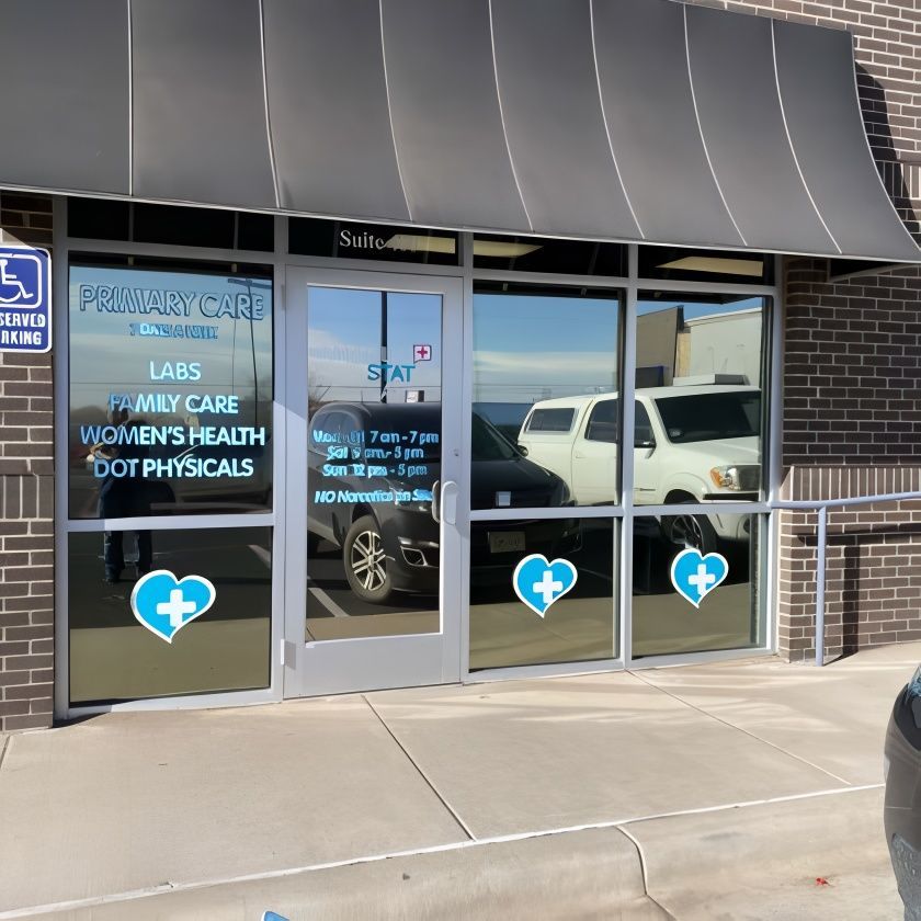 Medical clinic with glass windows, awning, and blue heart logos. Text: Primary Care, Labs, Family Care, Women's Health, and DOT Physicals.