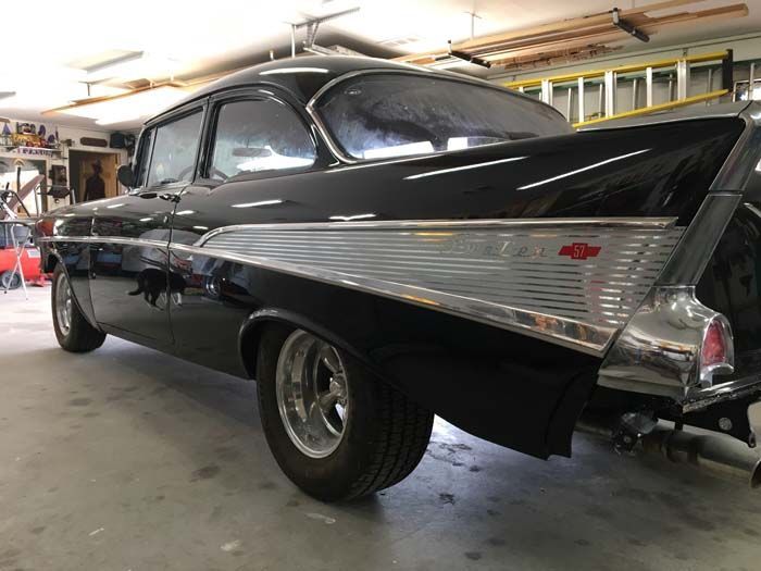 Black and chrome 1957 Chevrolet Bel Air coupe, parked in a garage.