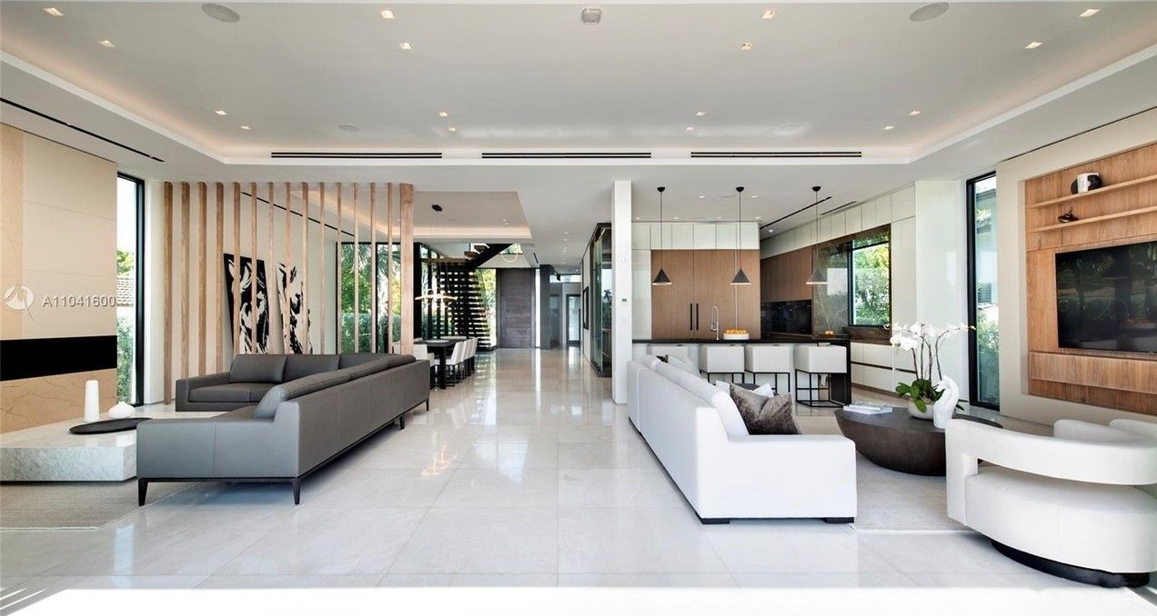 Modern living room with white floors, two gray sofas, open to kitchen and hallway.