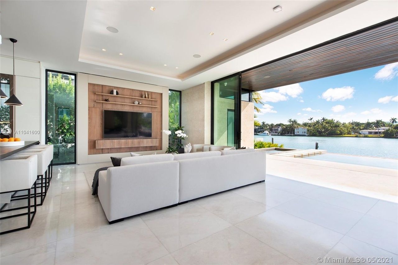 Spacious modern living room with water view, white sofa, and large sliding door.