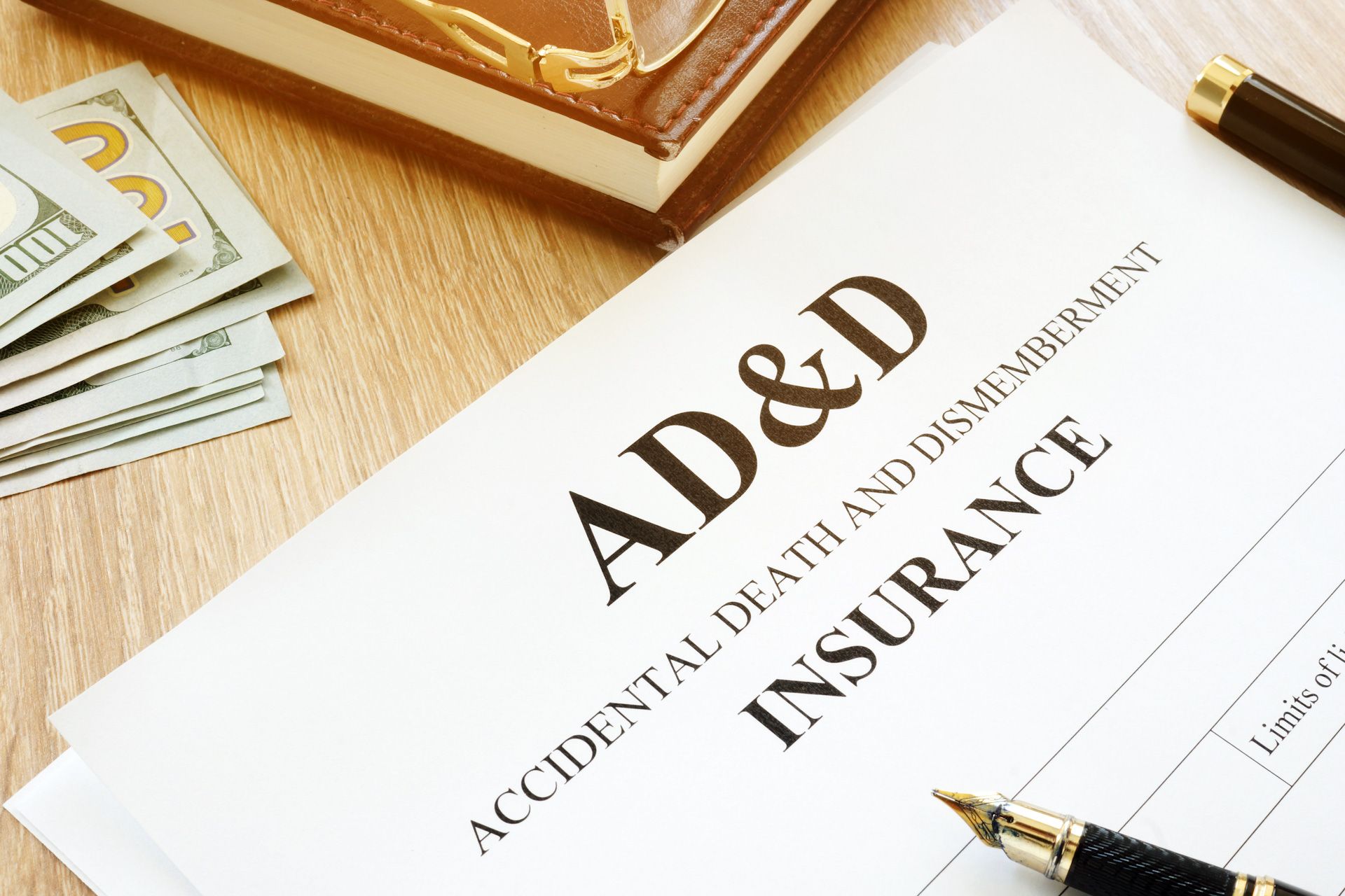 An ad and d insurance form with a pen and money on a wooden table.