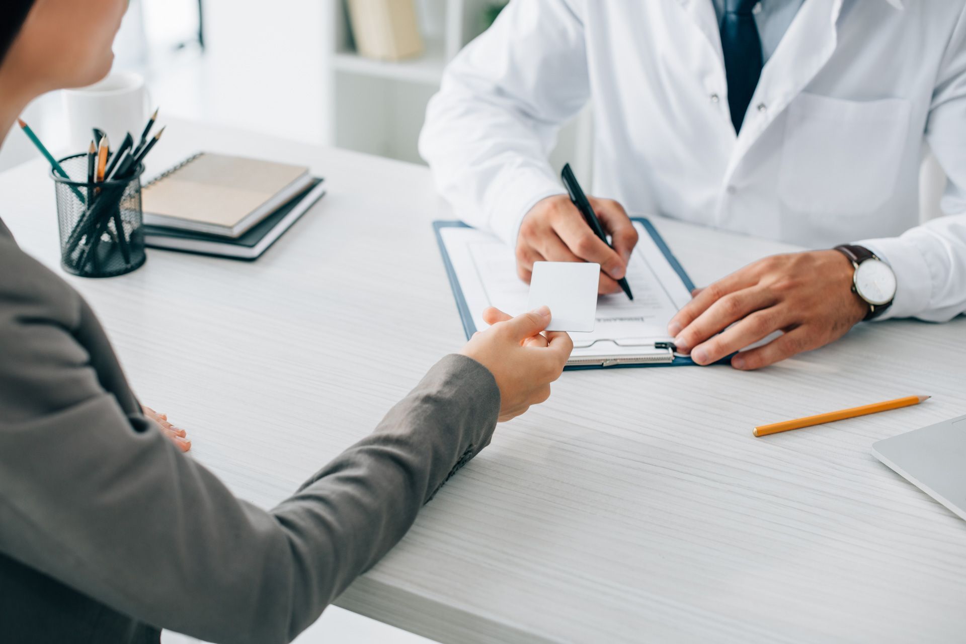 A doctor is giving a patient a prescription while sitting at a desk.