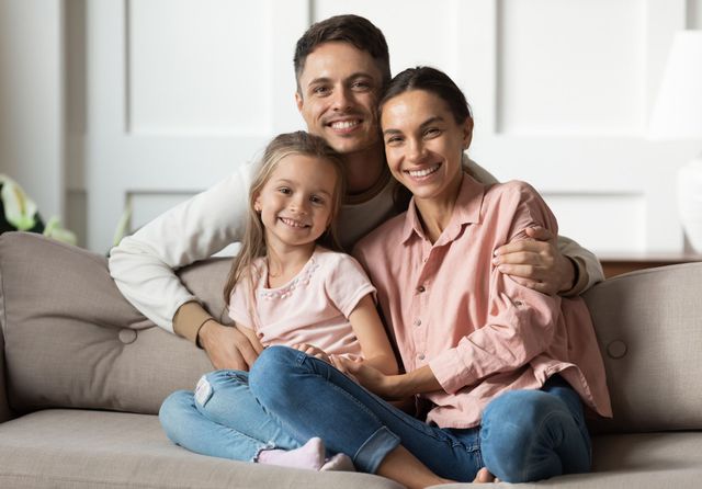 A family is sitting on a couch posing for a picture.