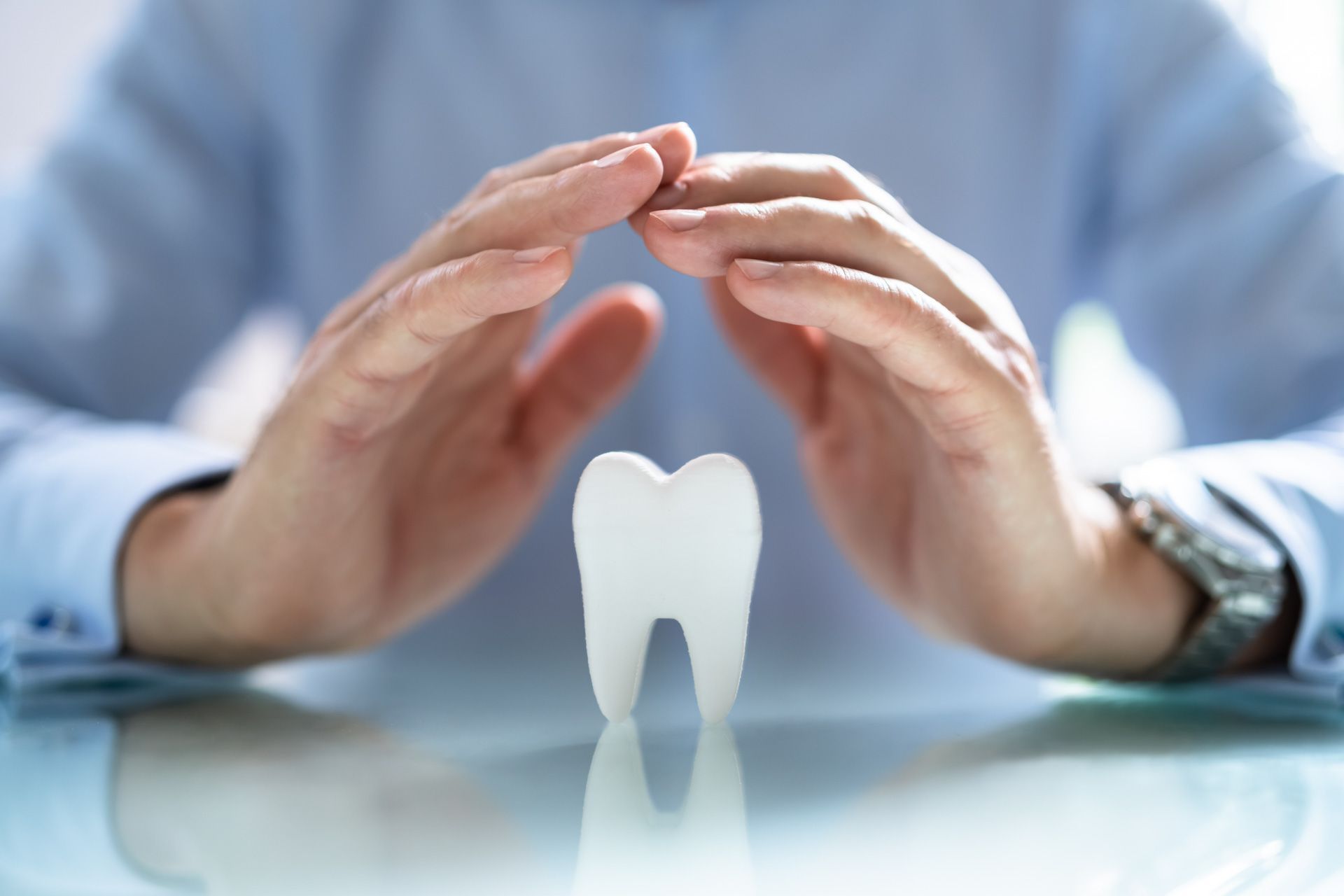 A man is covering a tooth with his hands.