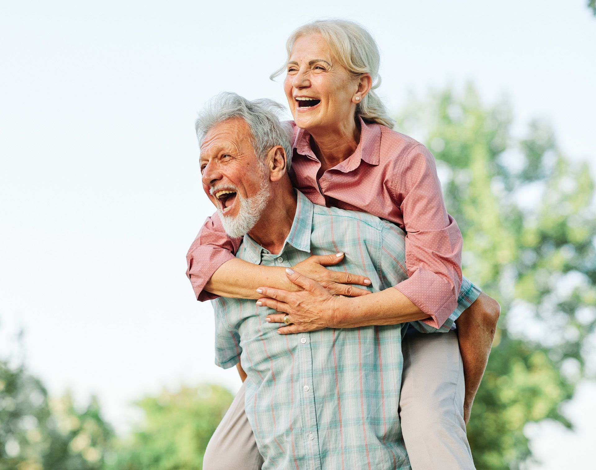A man is carrying a woman on his back in a park.