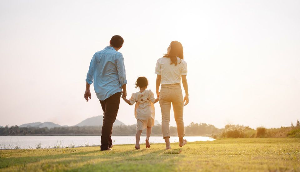 A family is walking in a park holding hands.