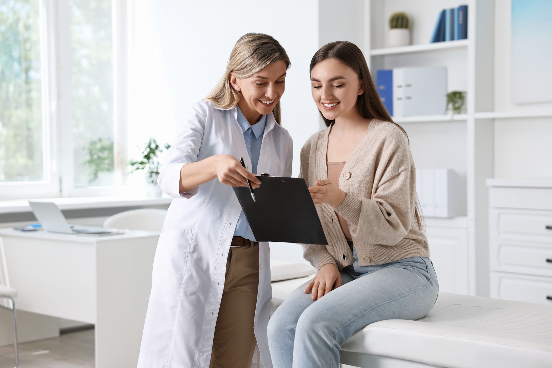 A doctor is talking to a patient who is sitting on a bed.