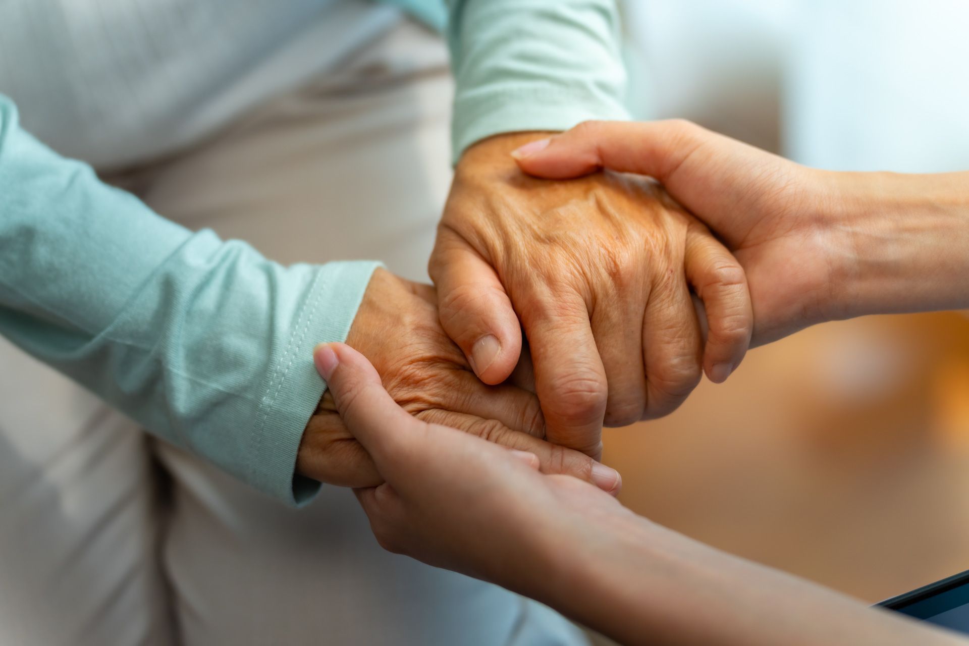 A woman is holding the hand of an older woman.