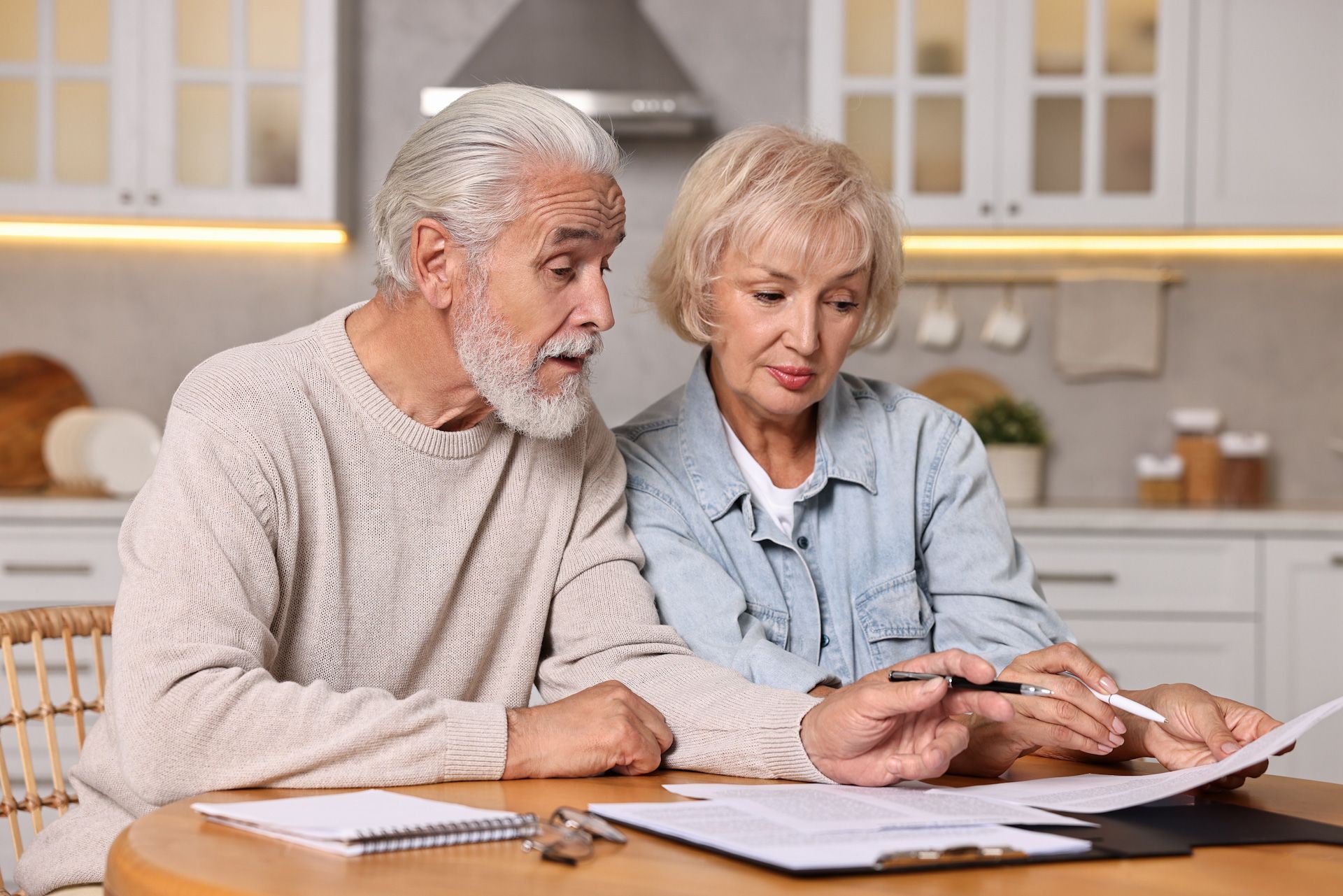 An elderly couple is sitting at a table looking at papers.