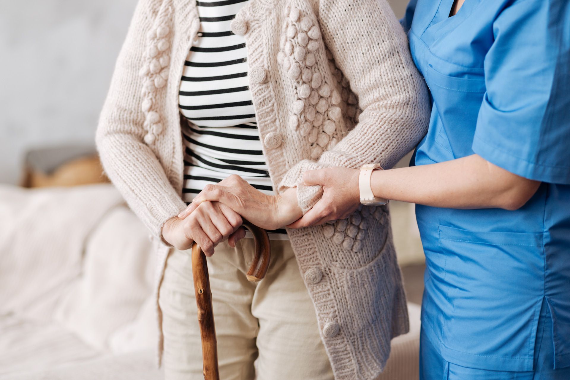 A nurse is helping an elderly woman with a cane.