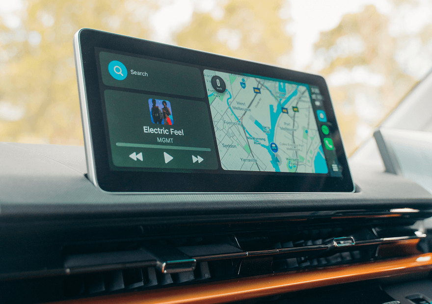 A dashboard touchscreen in a vehicle displaying an Android Auto interface with a music player and a navigation map.