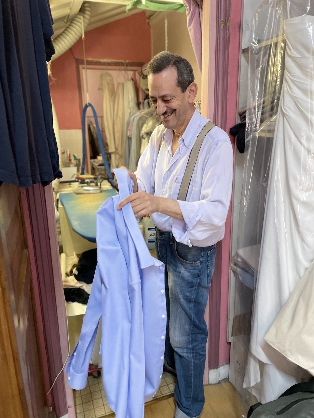 Un homme tient une chemise bleue dans une laverie automatique.