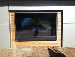 Storefront window with dark SkyVue sign set in a wood frame on a metal-sided building facade