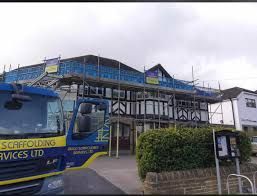 A scaffolding truck is parked in front of a building under construction.
