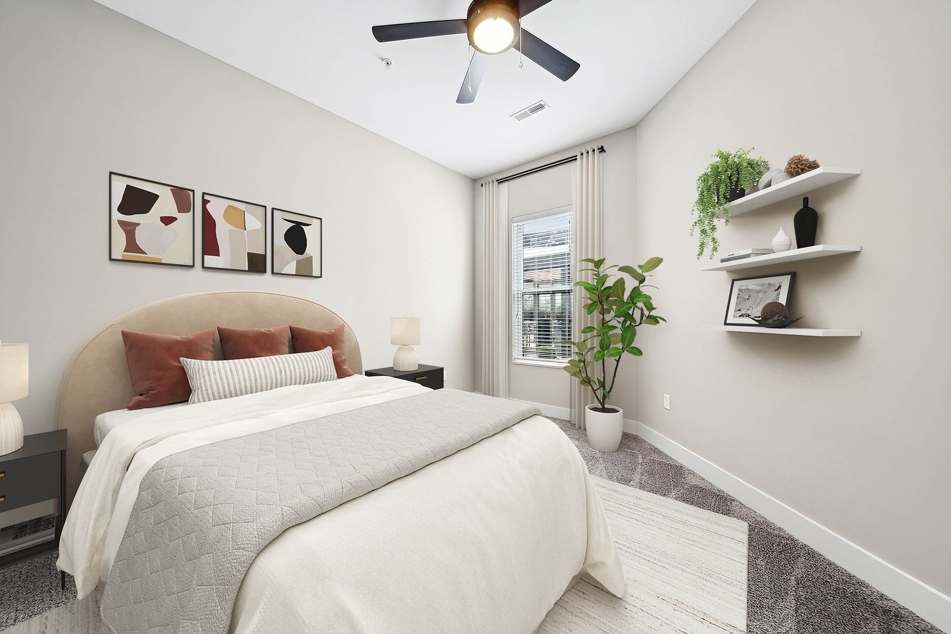 Bedroom in a modern apartment with a beige upholstered bed, abstract art above, and a ceiling fan.