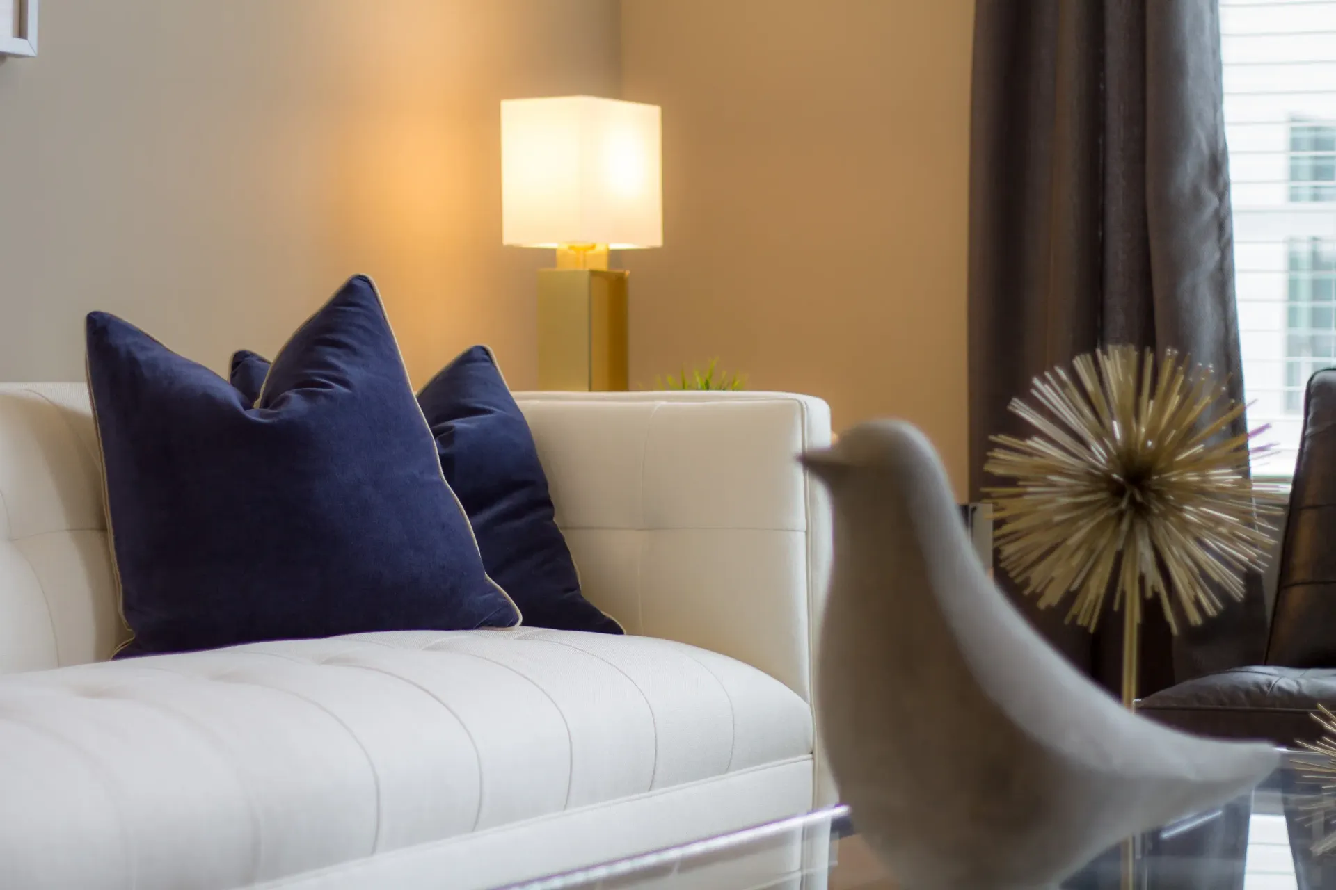 White sofa with navy cushions and a lamp in a modern living room.