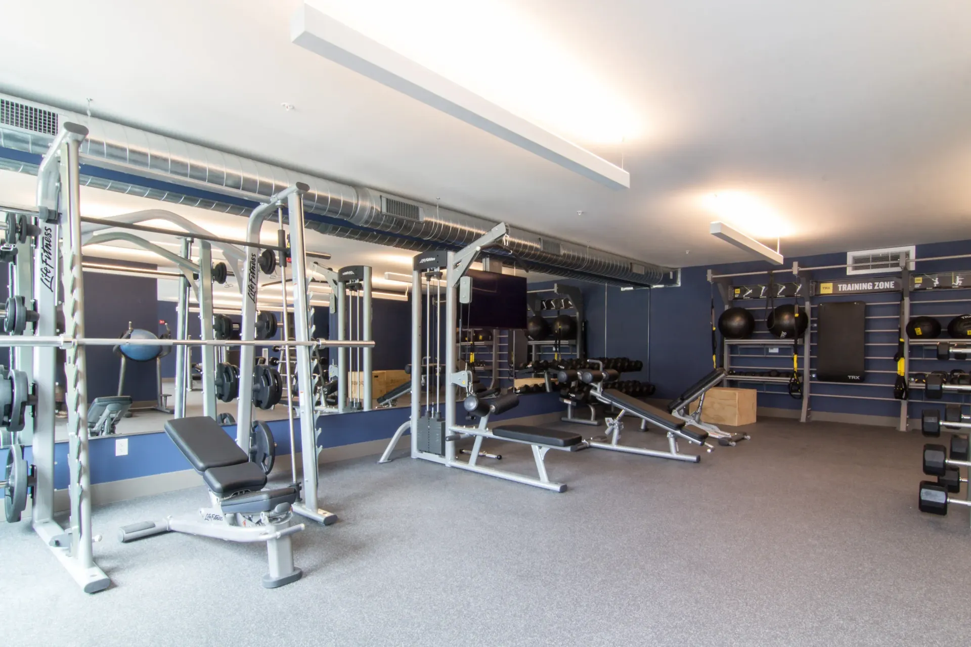 Indoor fitness center with weight machines, benches, and dumbbell racks.