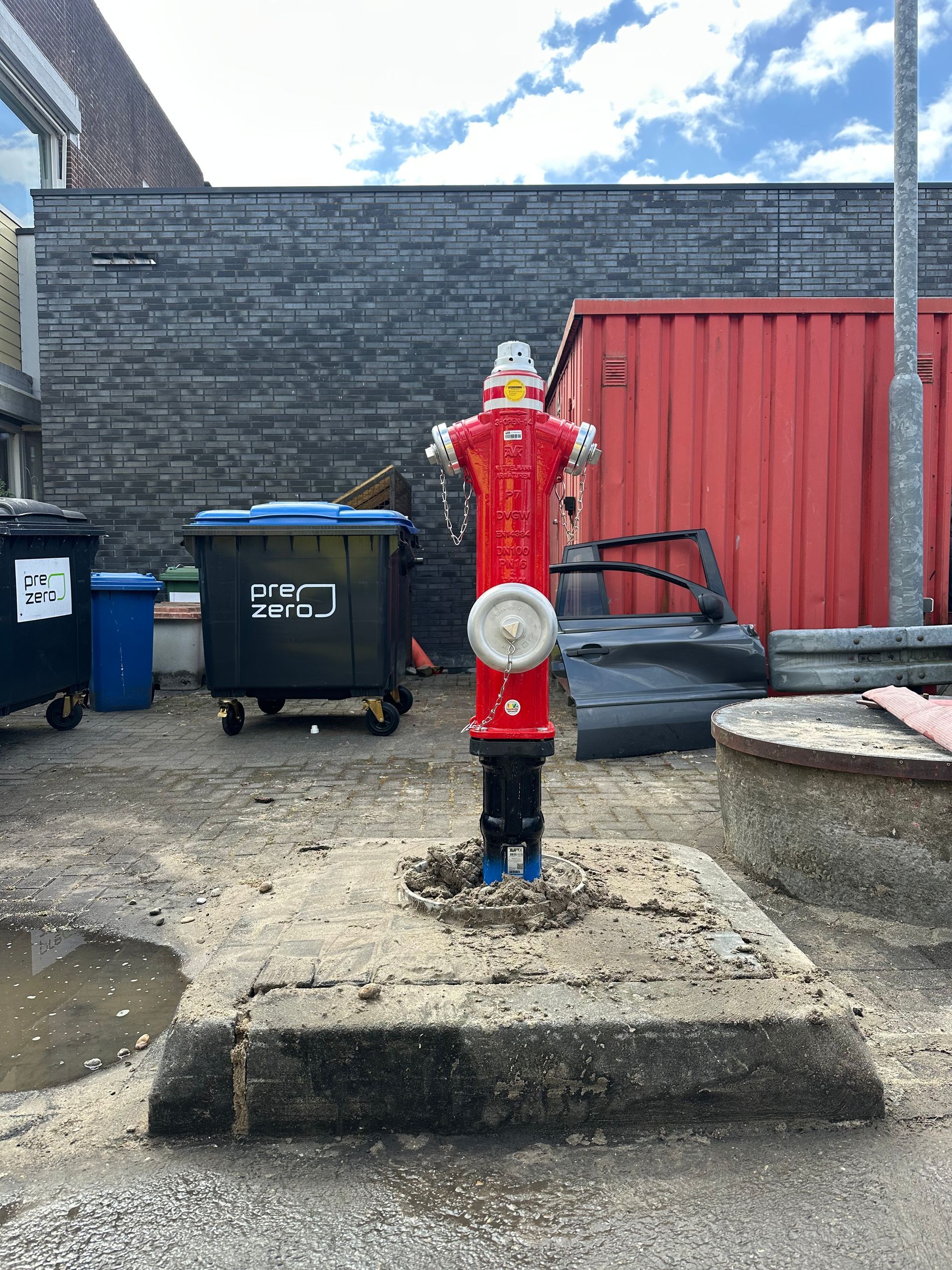 Een rode brandkraan staat midden op een parkeerplaats.