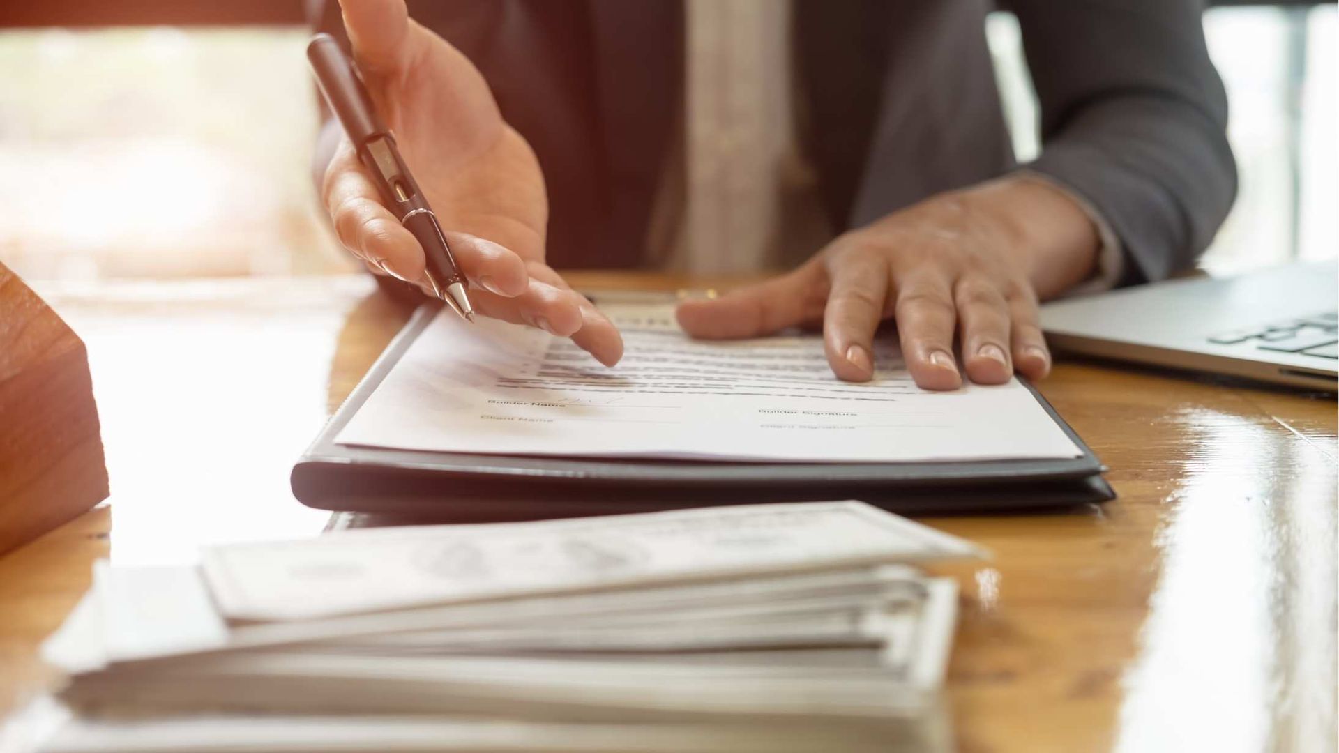 Person working on documents with a laptop, calculator, and phone on a table.