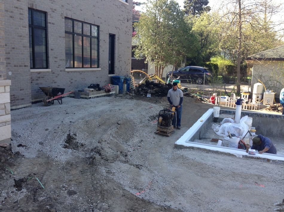 A man is standing next to a pile of dirt in front of a building.