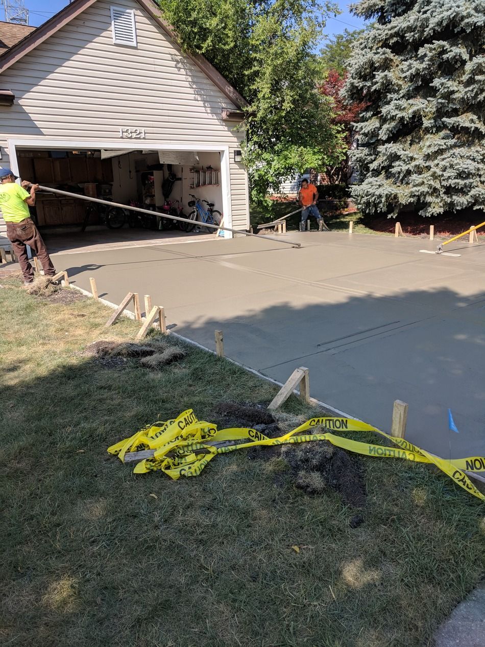 A concrete driveway is being built in front of a garage.