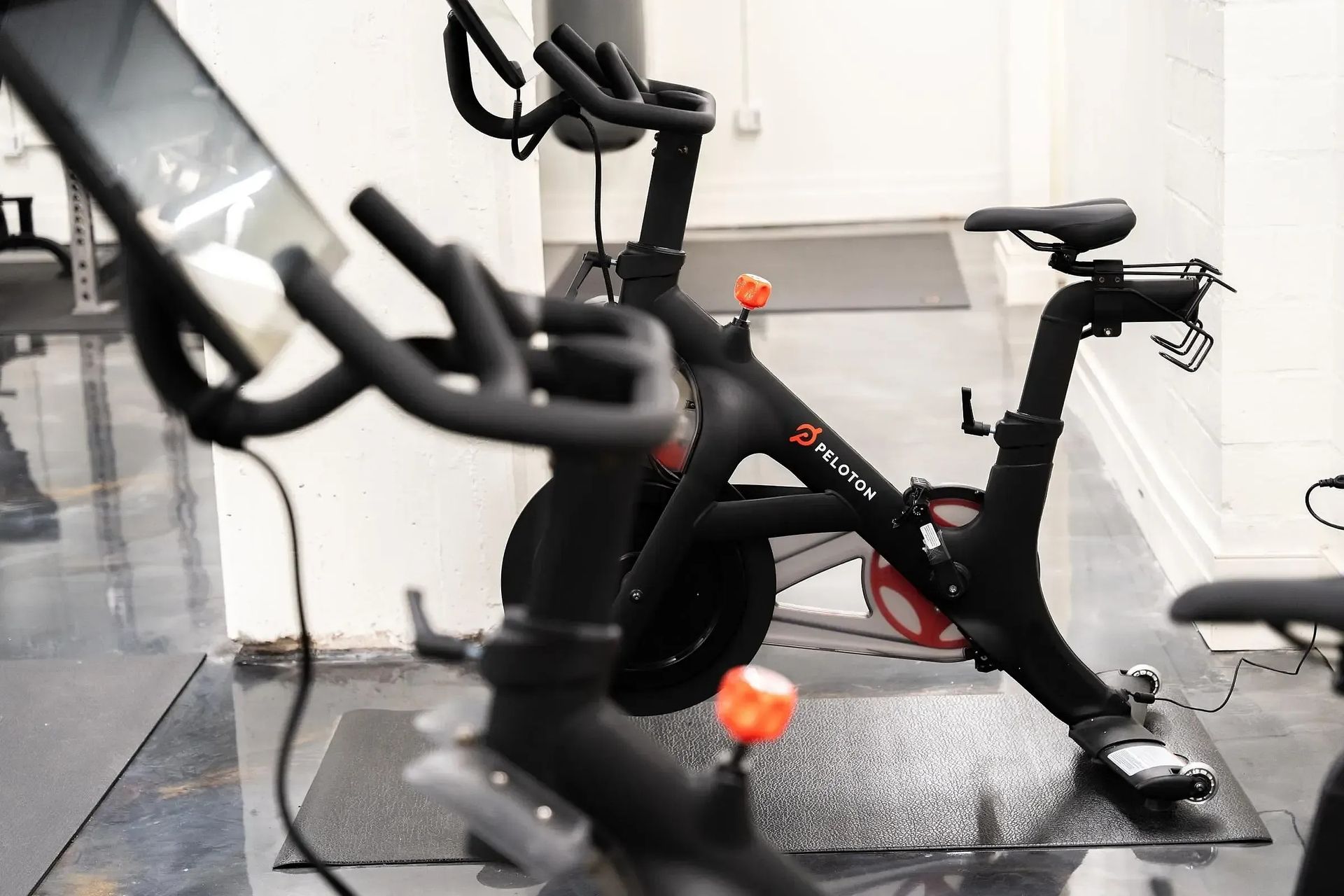 Peloton bikes in a studio, with large touchscreens and black frames.