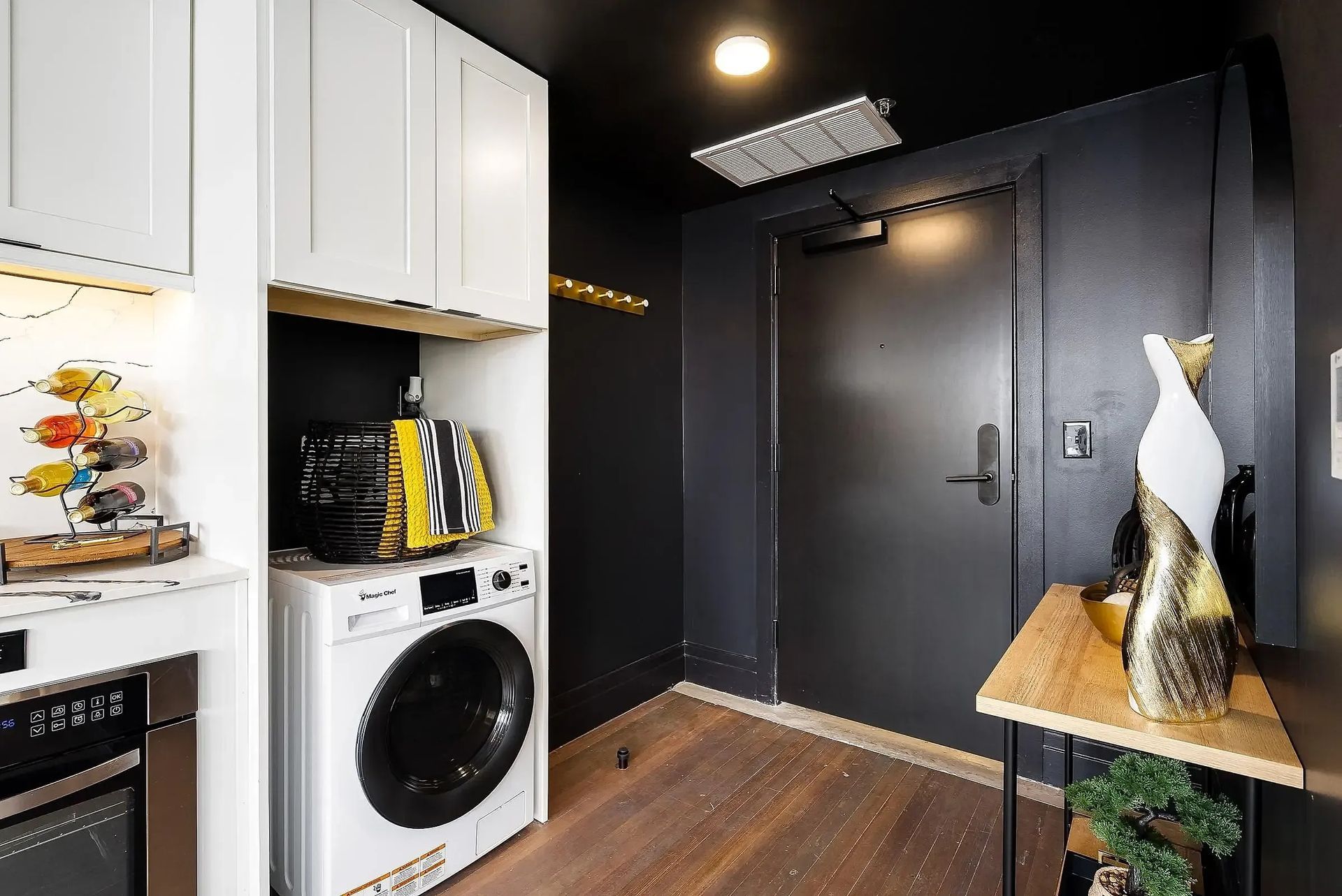 Laundry room with washer, cabinets, and black door.