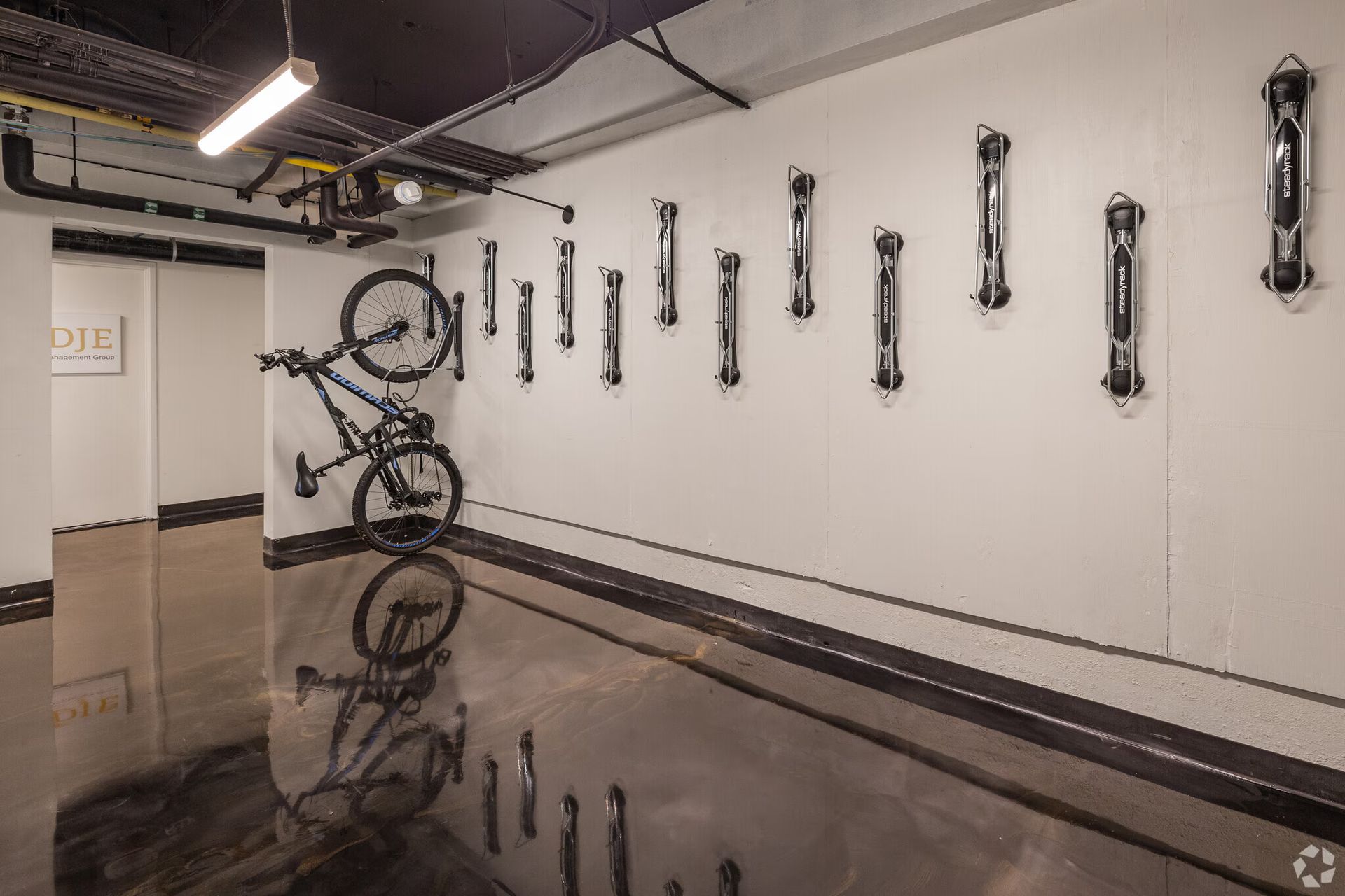 Bike storage room with bikes on wall racks, floor reflection, and air pumps aligned.