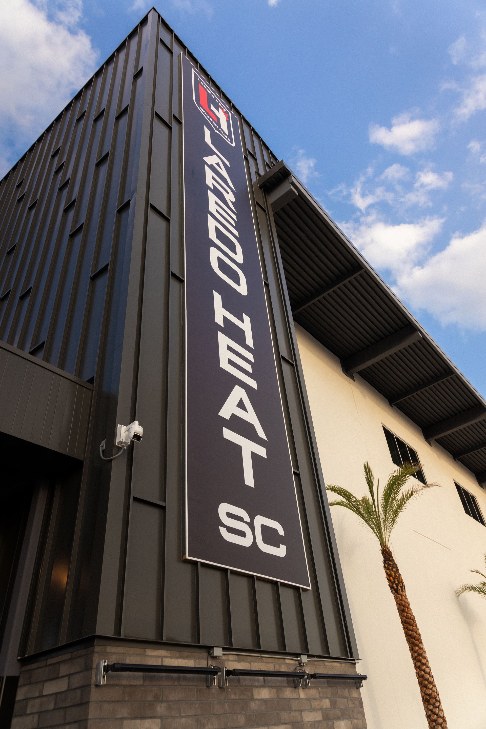 A Laredo Heat Soccer Club banner hanging from the side of their home stadium, the PEG Energy Stadium.
