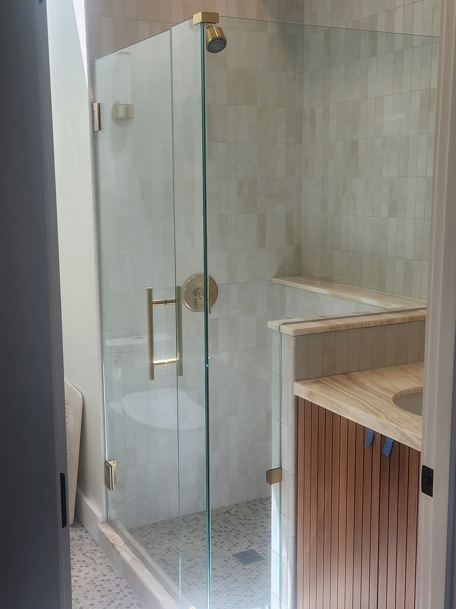 A bathroom with a glass shower door and a sink