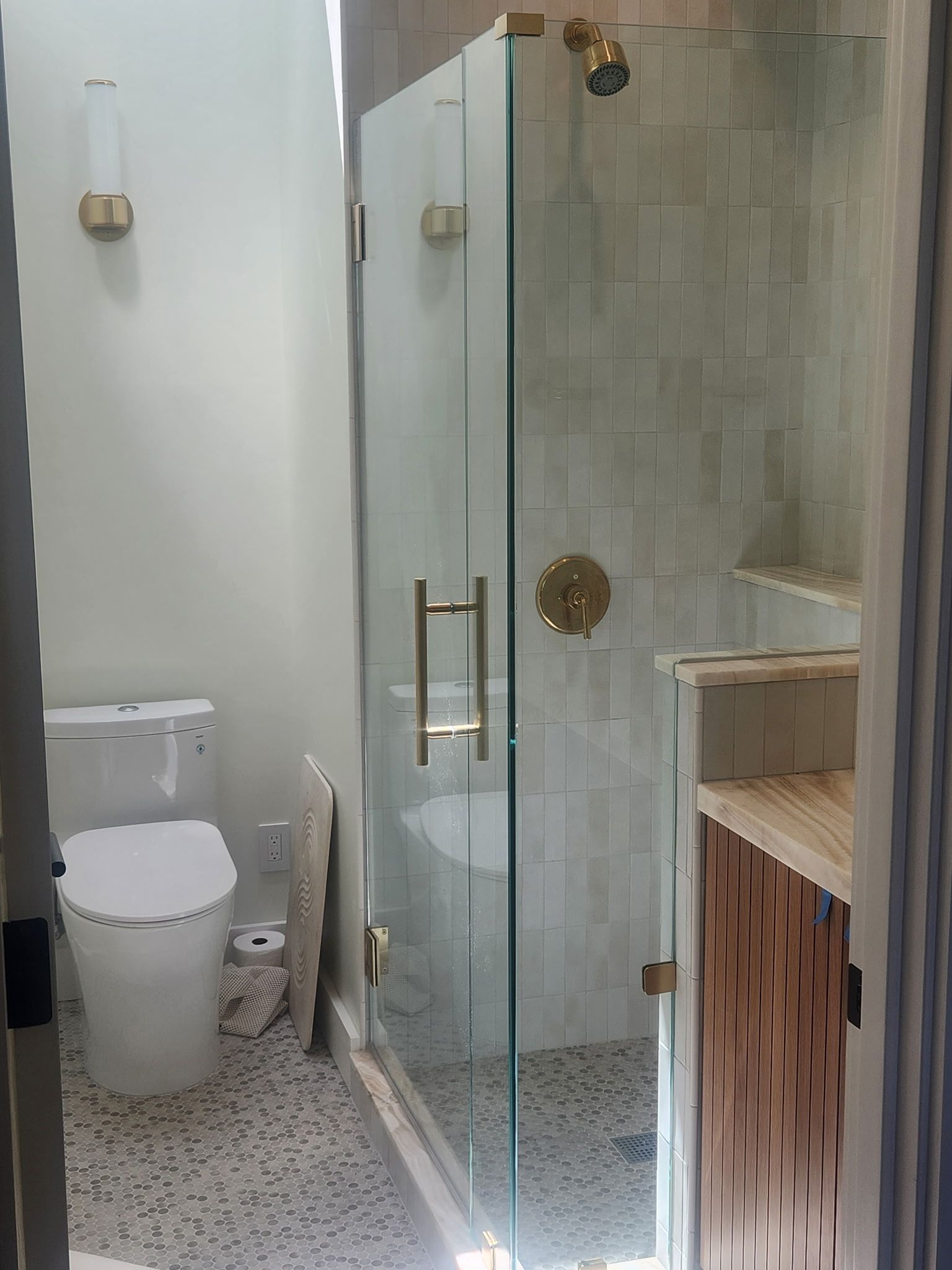 A bathroom with a toilet, sink and shower with a glass door.