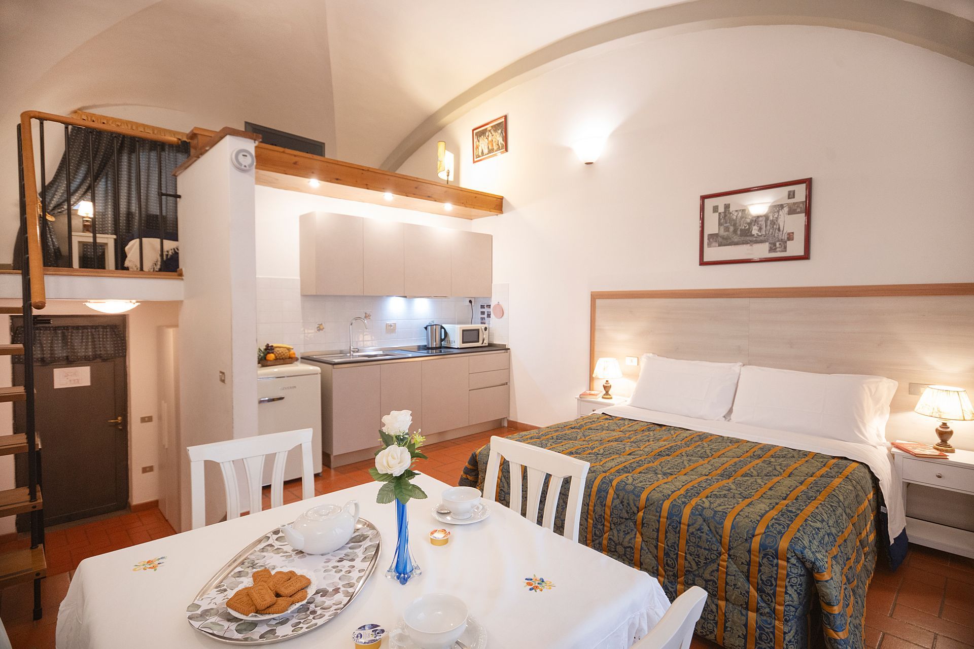 Cozy studio apartment with bed, dining table, kitchenette, and warm wood accents