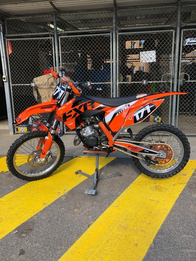 Orange and black dirt bike with rider number 171, on a stand, set in a shop. — Bodes All Mechanical In Bombala, NSW