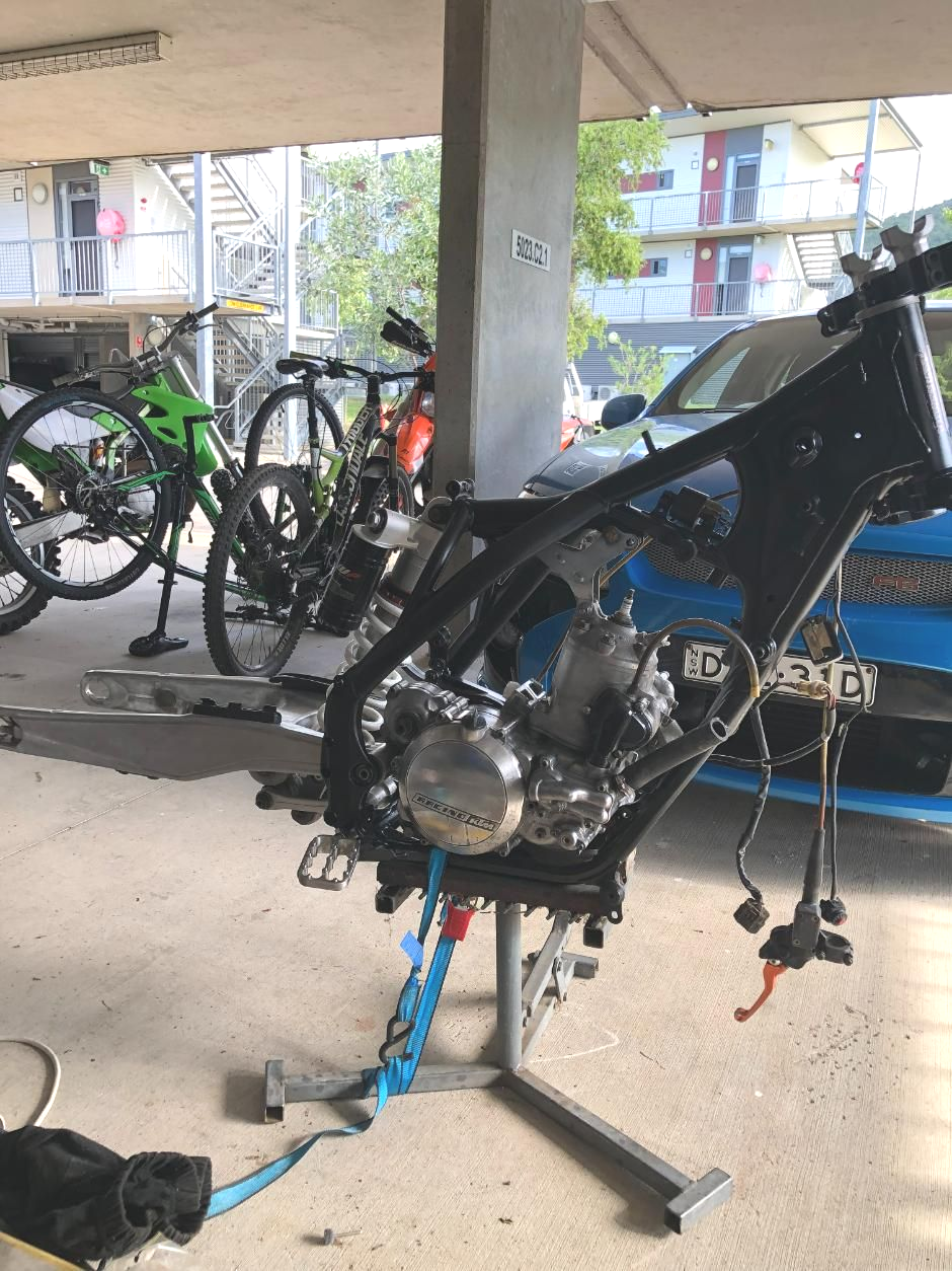 Dirt Bike Frame on a Stand, Engine Installed, Blue Straps, Garage Setting — Bodes All Mechanical In Pambula, NSW