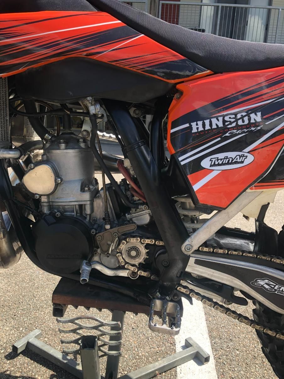 Orange and black dirt bike on a stand, side view. 