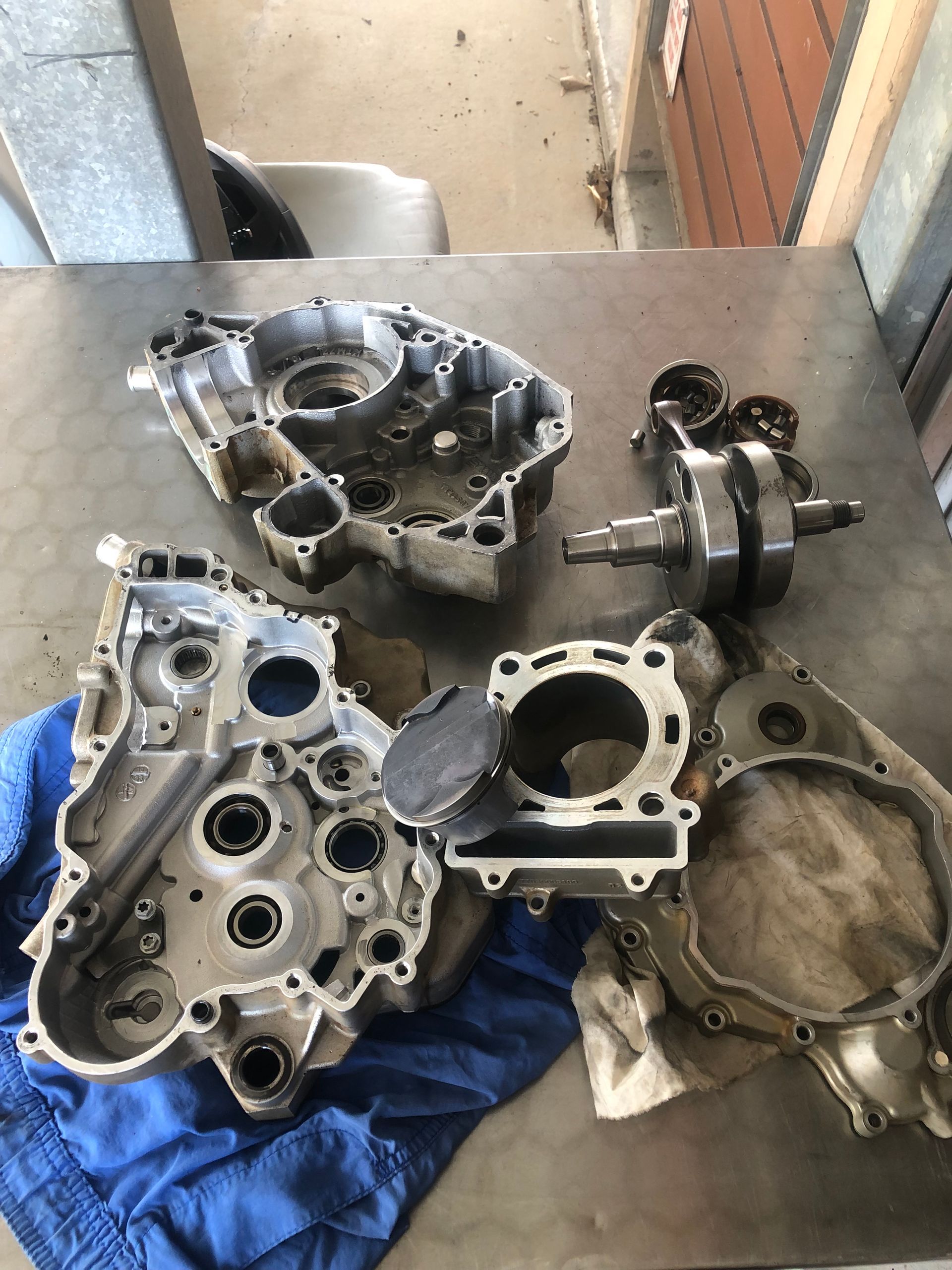 Motorcycle engine parts disassembled on a workbench. Includes crankcase, cylinder, crankshaft, pistons, and other components. — Bodes All Mechanical In Merimbula, NSW