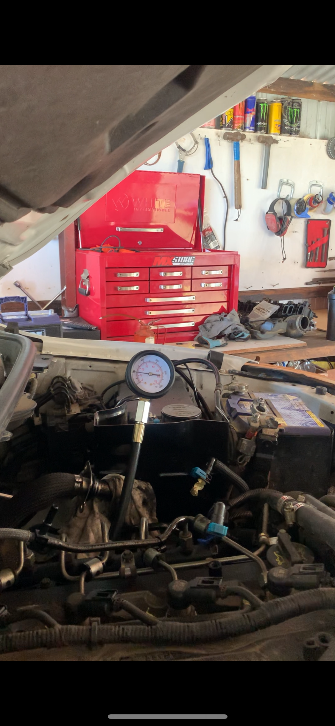 An open car hood with a pressure gauge connected to the engine. A red toolbox and tools are in the background. — Bodes All Mechanical In Tathra, NSW