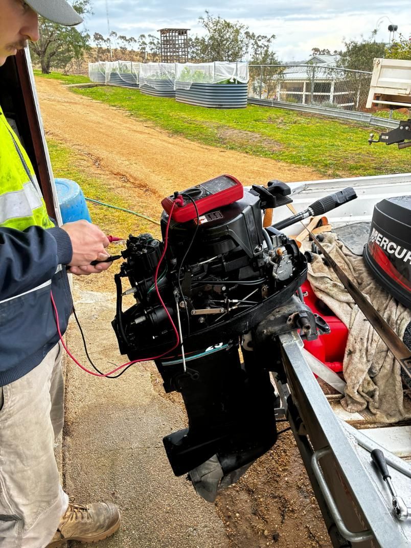 Man using a multimeter to test a boat motor; outdoors, daytime. — Bodes All Mechanical In Bermagui, NSW