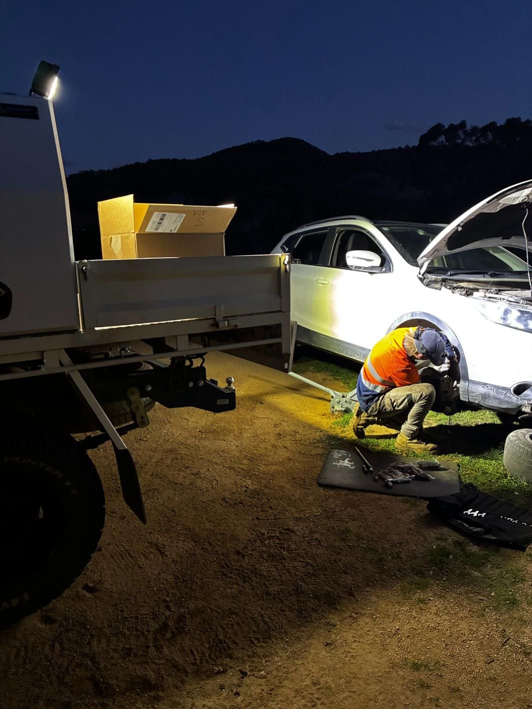 A Person Works on a White Car at Night, Illuminated by a Work Light — Bodes All Mechanical In Tantawangalo, NSW