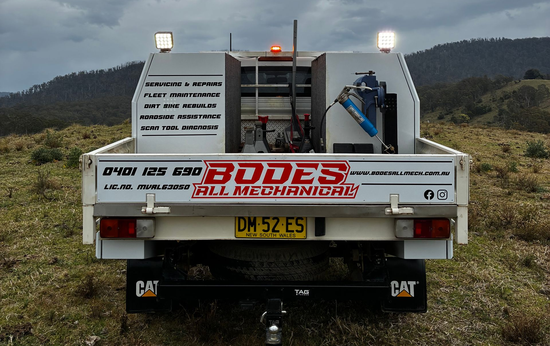 Rear view of a white service truck in a field, with tools, lights, and company branding. — Bodes All Mechanical In Tantawangalo, NSW