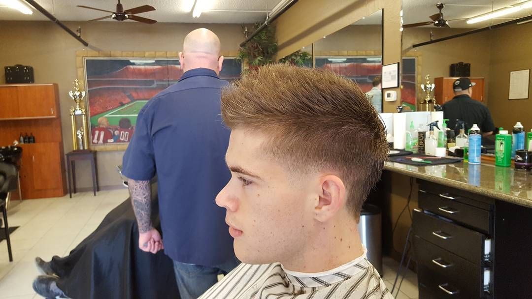 A man is getting his hair cut at a barber shop.